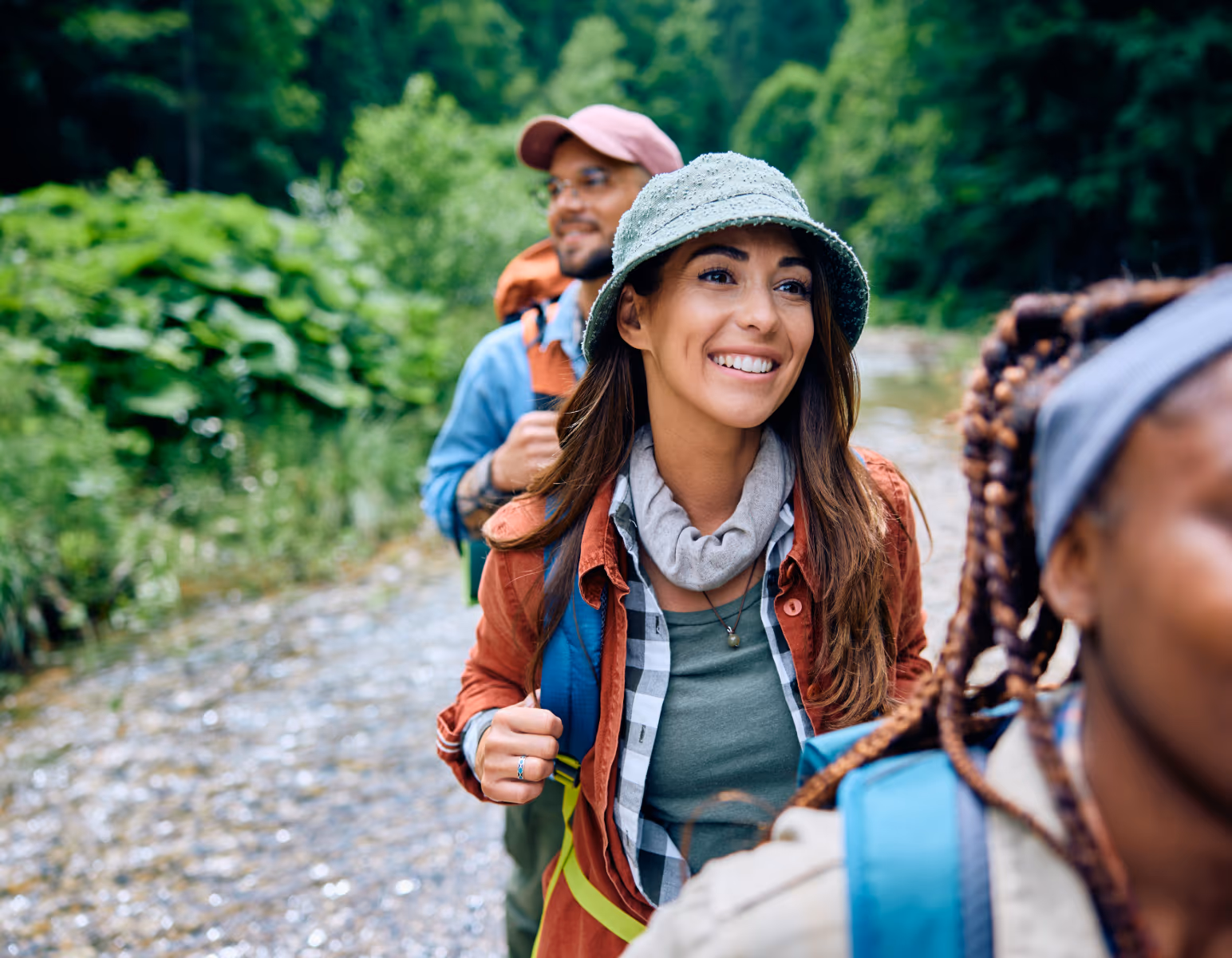 Smiling travellers hiking together through green hills